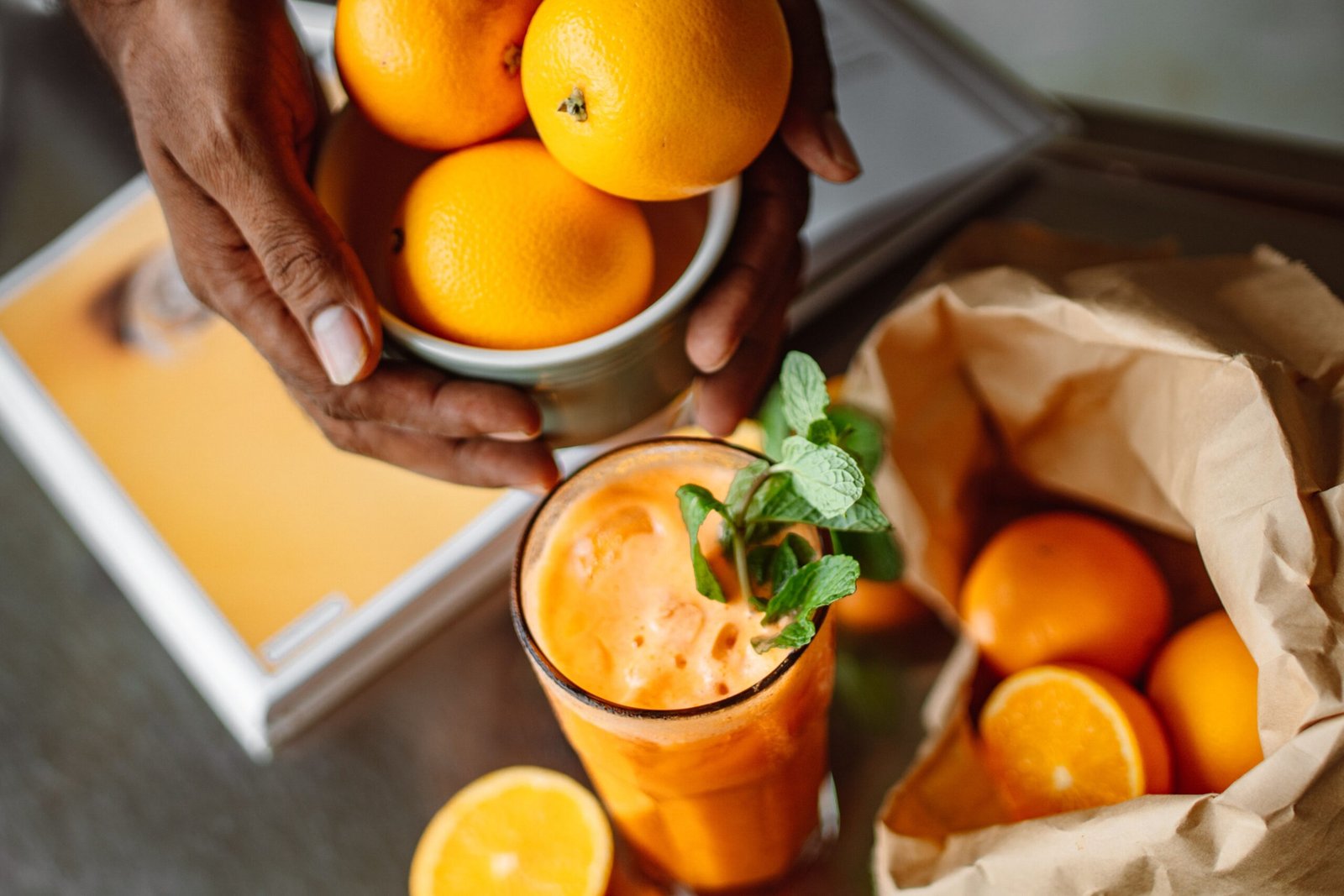 Refreshing orange juice garnished with mint, surrounded by fresh whole oranges. Perfect for health and lifestyle concepts.